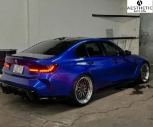 view of the detailed blue BMW sports sedan parked inside the detailing bay under overhead garage lighting, referencing auction prep