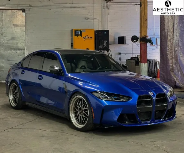view of the detailed blue BMW sports sedan parked inside the detailing bay under overhead garage lighting, referencing auction prep